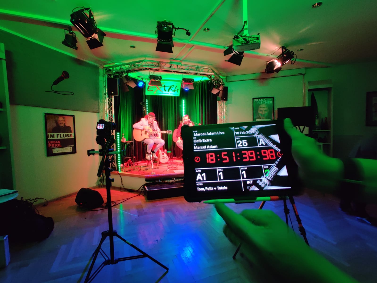 Bild von Aufnahme-Tag, Online Konzert Marcel Adam. Er ist im Hintergrund zu sehen. Im Vordergrund ist eine Regieklappe.