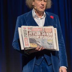Ein Mann in blauem Samtanzug und einer Bild Zeitung in der Hand.