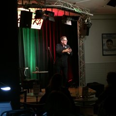 Ein Mann in schwarzem Hemd und schwarzer Hose auf der Bühne.