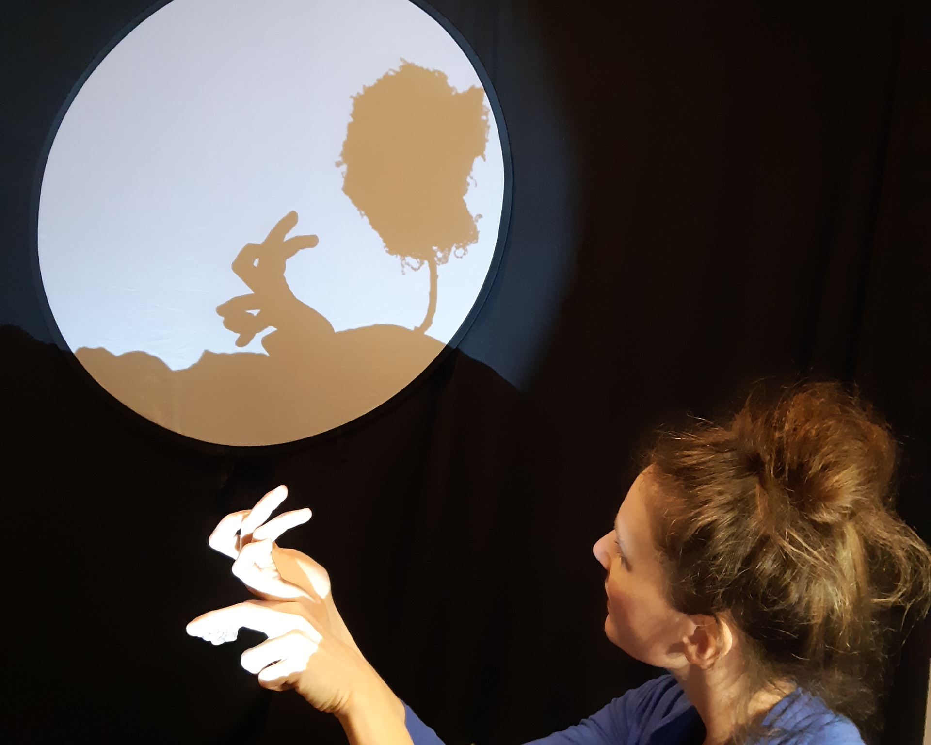 Frau, die mit ihren Fingern einen Hasen als Schatten projiziert