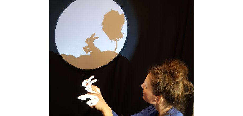 Frau, die mit ihren Fingern einen Hasen als Schatten projiziert