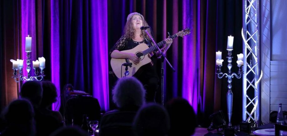 Haigis gibt ein Konzert im Café Extra, sie spielt Gitarre und singt.