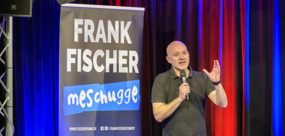 Ein Mann macht Stand-up auf der Bühne.