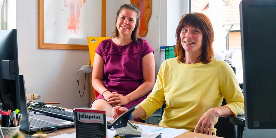Jana Schäfer ist links im Bild, Claudia Weller rechts. Sie sitzen neben einander im Büro. 