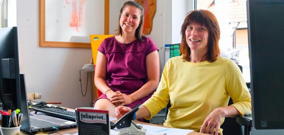 Jana Schäfer ist links im Bild, Claudia Weller rechts. Sie sitzen neben einander im Büro. 