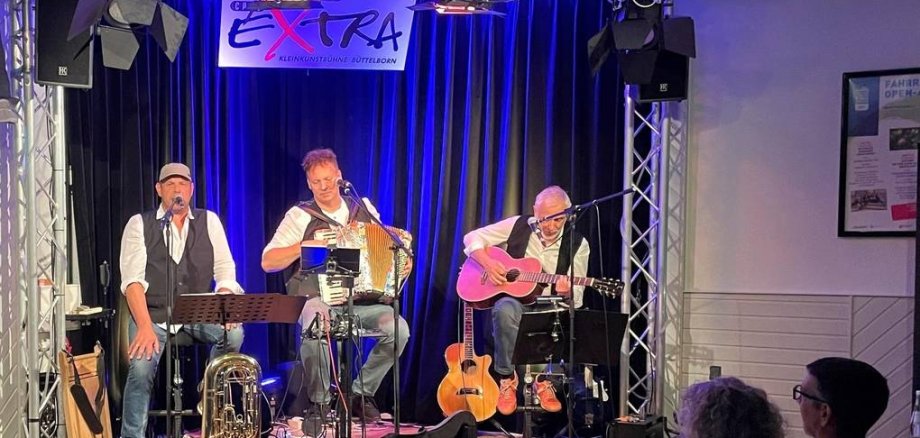 Fred Kraus, Ralf Baiting und Bodo Kolbe sitzen auf der Bühne und machen Musik.
