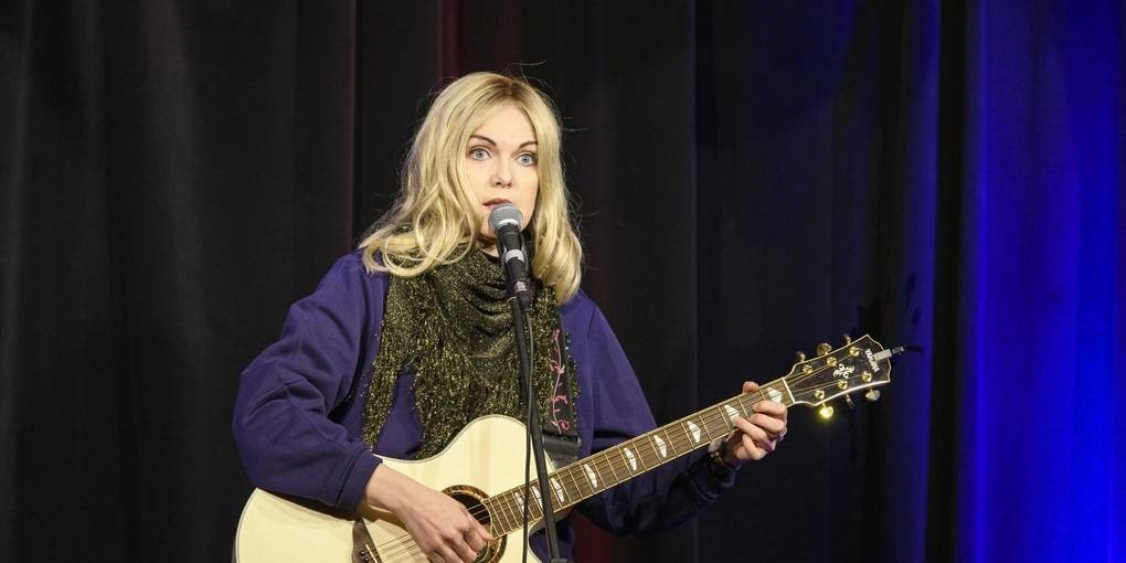 Eine Frau spielt Gitarre und singt.
