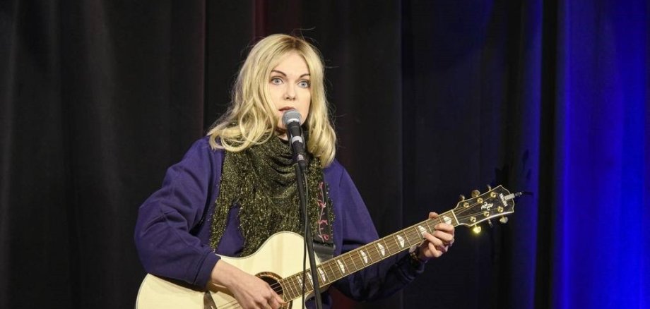 Eine Frau spielt Gitarre und singt.